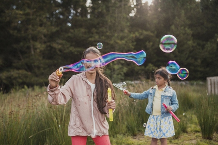 Two little girls creating bubbles in the woodlands on their holiday.の写真素材