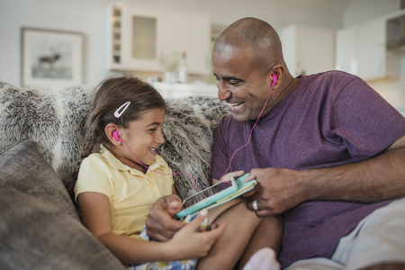 Father and daughter laughing together, using a digital touch screen tablet.の写真素材