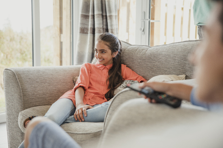 Female teenager relaxing on vacation, sitting on the sofa and laughing.の写真素材