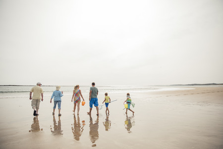 Rear view of a family walking down to the waters edge while on holiday.の写真素材