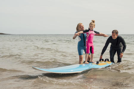Parents teaching little girl how to surf at the beach.の写真素材