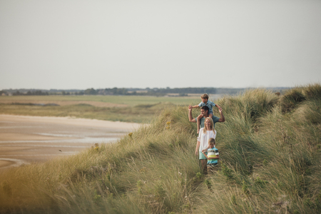 Wide angle view of a family walking through the sand dunes at the beach while on holiday.の写真素材