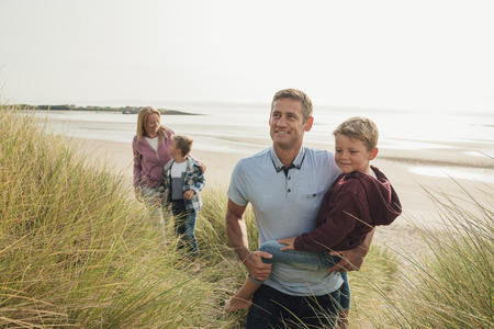 Family with two children walking up the sand dune.の写真素材