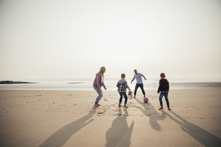 Wide angle view of a family playing football at the beach.の写真素材