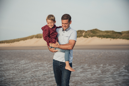 Father and son spending some time together, walking down the beach on holiday.の写真素材