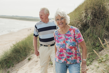 Front view of an elderly couple relaxing at the beach while on holiday.の写真素材