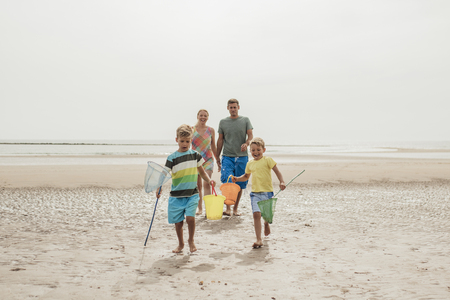 Front view of family walking up the beach with buckets and fishing nets.の写真素材