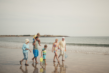 Three generation family walking along the seafront while on a beach holiday.の写真素材