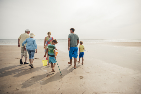 Rear view of a family walking down to the waters edge while on holiday.の写真素材