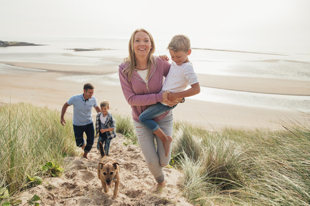 High angle view of family walking up a sand dune at the beach.の写真素材