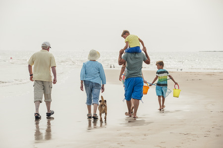 Rear view of a family walking to the sea front while on holiday at the seaside.の写真素材