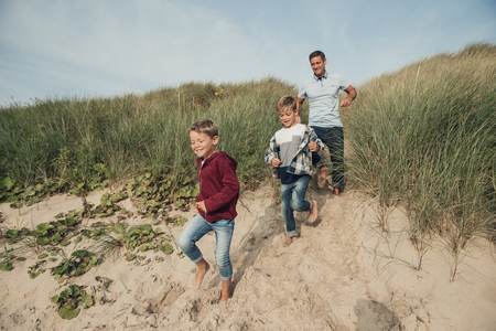 Family walking down to the sea front from the sand dunes.の写真素材