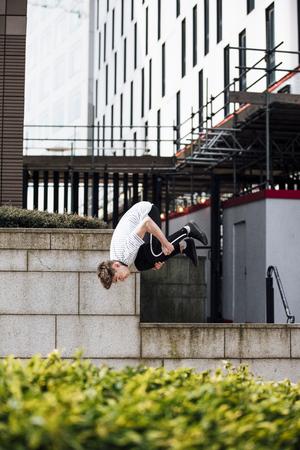 Freerunner is doing a flip from a wall in the city. の写真素材