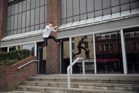 Freerunner is jumping between walls and railings in the city.の写真素材