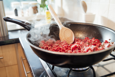 Beef mince and onions browning off in a wok on a home cooker. の写真素材