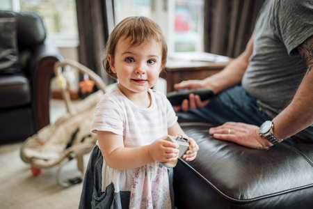 Little girl has stopped playing with her father at home to look at the camera. She is holding a toy.の写真素材