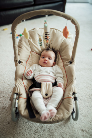 Portrait of a baby girl in her bouncer chair at home.の写真素材