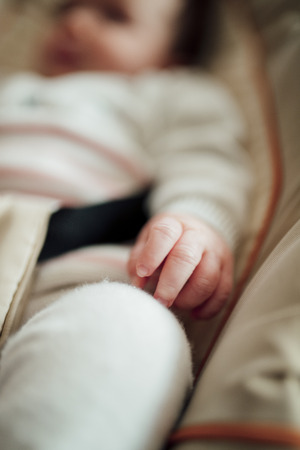 Close up shot of a babies hand while she is sleeping in her bouncer chair.の写真素材
