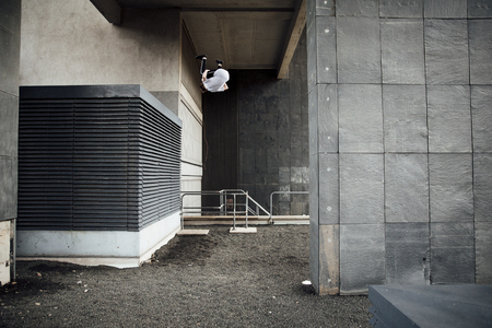 Young freerunner is doing a flip from a rooftop vent in the city.の写真素材