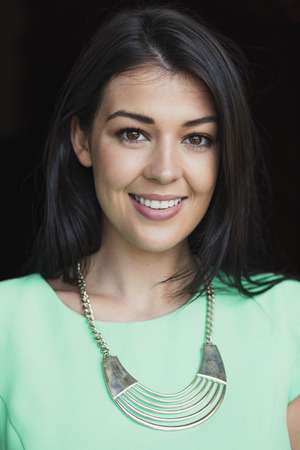 Headshot of a beautiful young woman wearing a necklace and smiling for the camera.の写真素材