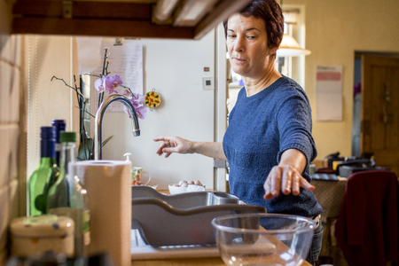 Woman reaches towards a glass bowl as she prepares dinner for Thanksgiving.の写真素材