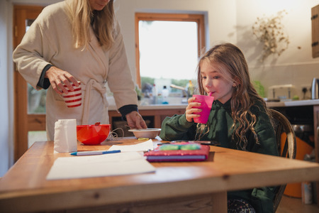 Mother cleaning up after her daughter has finished breakfastの写真素材