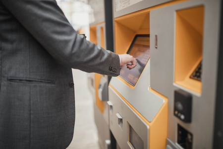 Unrecognisable person using a touch screen ticket machine and selecting which ticket they want.の写真素材