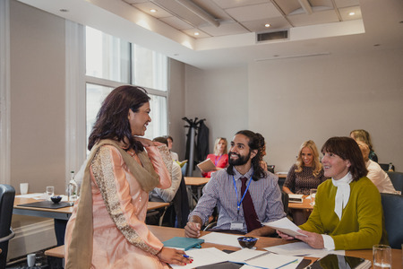 Multiracial group talking over their notes after a presentation at a conference.
