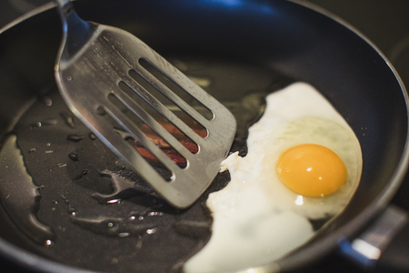 Close-up of an egg being fried. Going to be picked out with the spatula.の写真素材