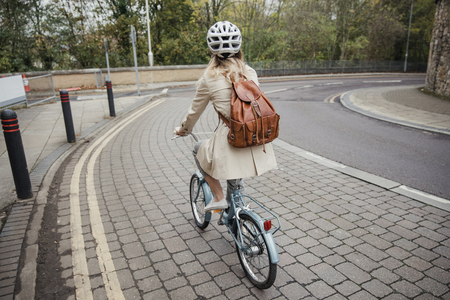Rear view of an unrecognisable person cycling down the street on the way to work.の写真素材