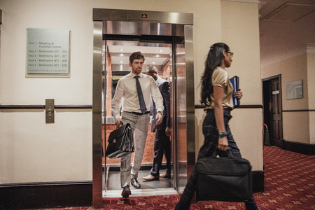 Businessmen and businesswomen walking out the lift at the hotel after a business meeting.の写真素材