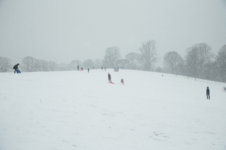 People are outdoors enjoying the snowy weather with sleighs and snow toys.の写真素材