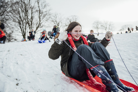 Close up shot of a little girl on a snow sled in a community race.