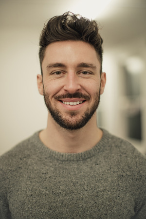 Front view of a young male adult looking and smiling at the camera while he gets a portrait taken.の写真素材