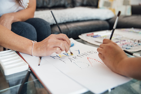 Close up shot of a little boy and his mother making a Father's Day card at home.の写真素材