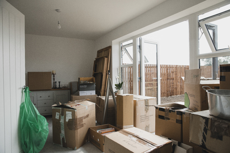 Dining room is full of furniture and cardboard boxes as a family are moving in.の写真素材