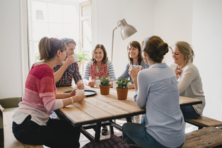 Group of employees at a small coffee shop sitting around a table having a meeting.の写真素材