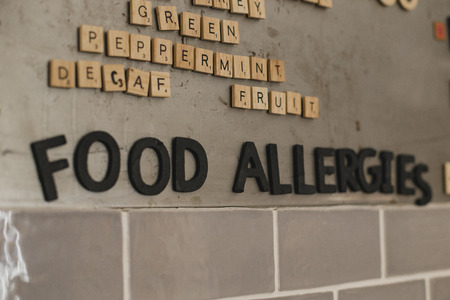 Low angle view of food allergies menu on the wall in a cafe. They have used little tile letters to show the words.の写真素材