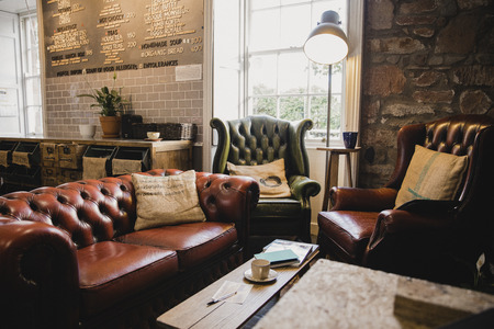 Empty interior of a small cafe, there is a seating area with leather sofas and a wooden table.