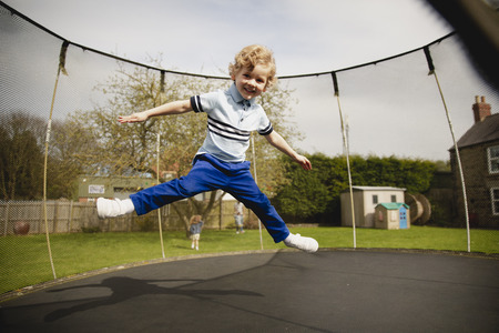 Little boy playing on a tramploine outside. He is having fun and being playful.の写真素材