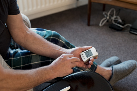 Close up shot of a senior man checking his blood glucose levels at home with a monitor.