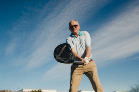 Ball perspective shot of a senior man swinging a golf club.
