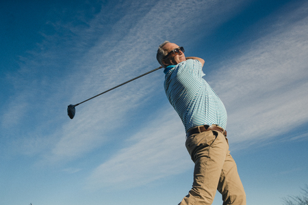 Ball perspective shot of a senior man swinging a golf club.の写真素材