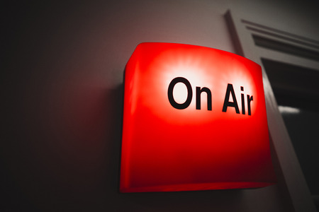 A close-up shot of a red on air sign on a wall in a recording studio.