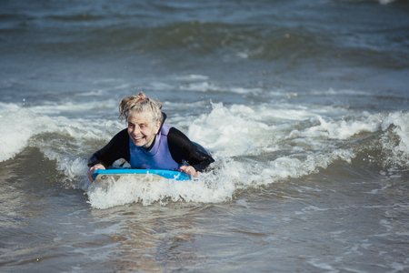 Mature woman having fun on a bodyboard in the sea.の写真素材