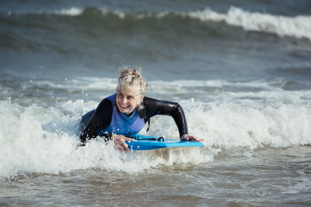 Mature woman having fun on a bodyboard in the sea.