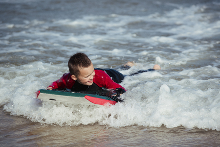 Little boy is bodyboarding in the sea.の写真素材