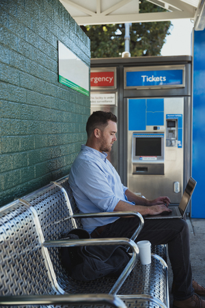 A side-view shot of a mid-adult caucasian businessman working on his laptop while he is sitting...