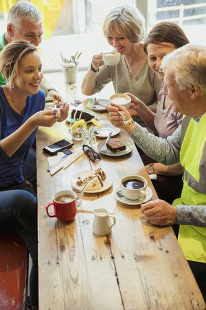 A group of five people taking a break from city cleaning and having coffee and cake.