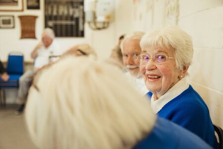 A clsoe up shot of a senior woman sitting with friends, looking at the camera.の写真素材